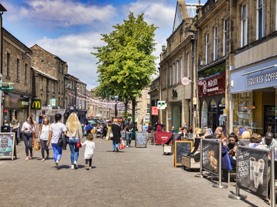 Lancaster Historic Shopping City- A busy day in Cheapside, the main shopping street of the historic town, on a bright sunny day, with people shopping and sitting outside cafes drinking coffee.